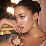 Charlotte Tilbury Hollywood Glow Glide highlighter in Pillow Talk Glow with model wearing glamorous makeup