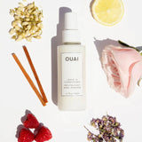 Woman applying OUAI Leave In Conditioner spray to damp hair for detangling and heat protection