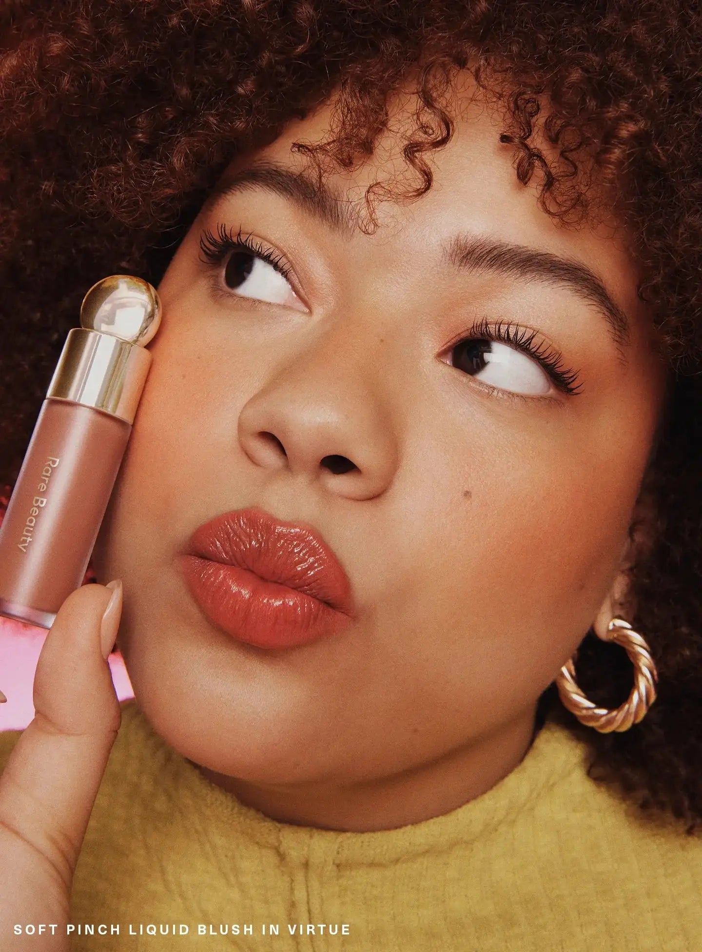 Model wearing Rare Beauty Soft Pinch Liquid Blush in Virtue dewy beige peach on cheeks