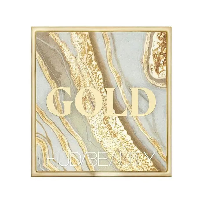 Lifestyle image of Huda Beauty Gold Obsessions palette paired with makeup brush and accessories
