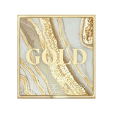 Lifestyle image of Huda Beauty Gold Obsessions palette paired with makeup brush and accessories